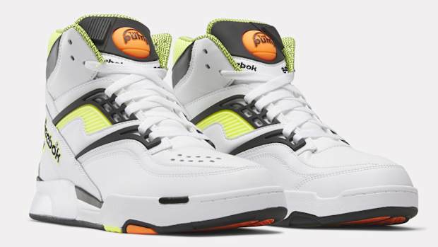 Side view of white, black, and yellow Reebok shoes.